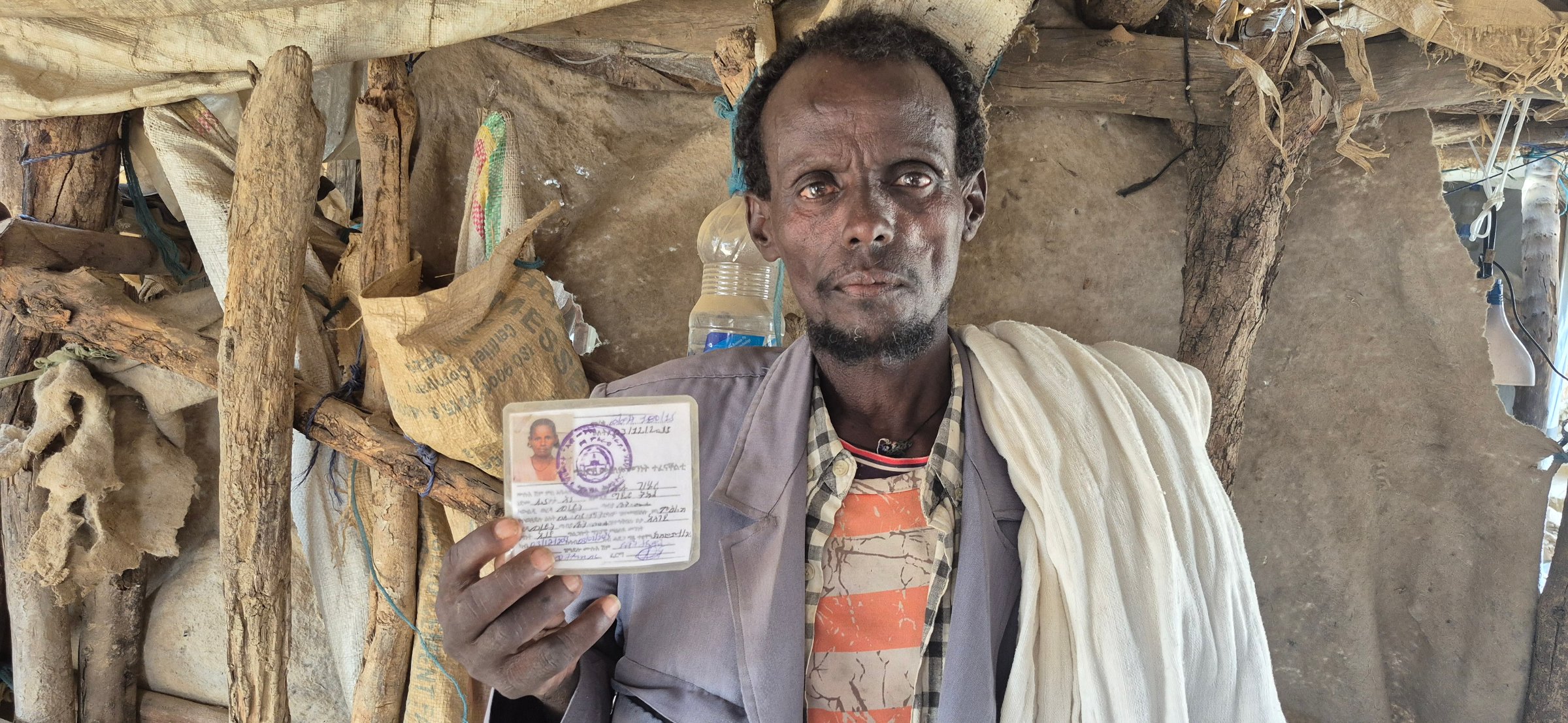Tesheger Tagegne holds up the identity card of his wife, who died of a malnutrition-related illness.