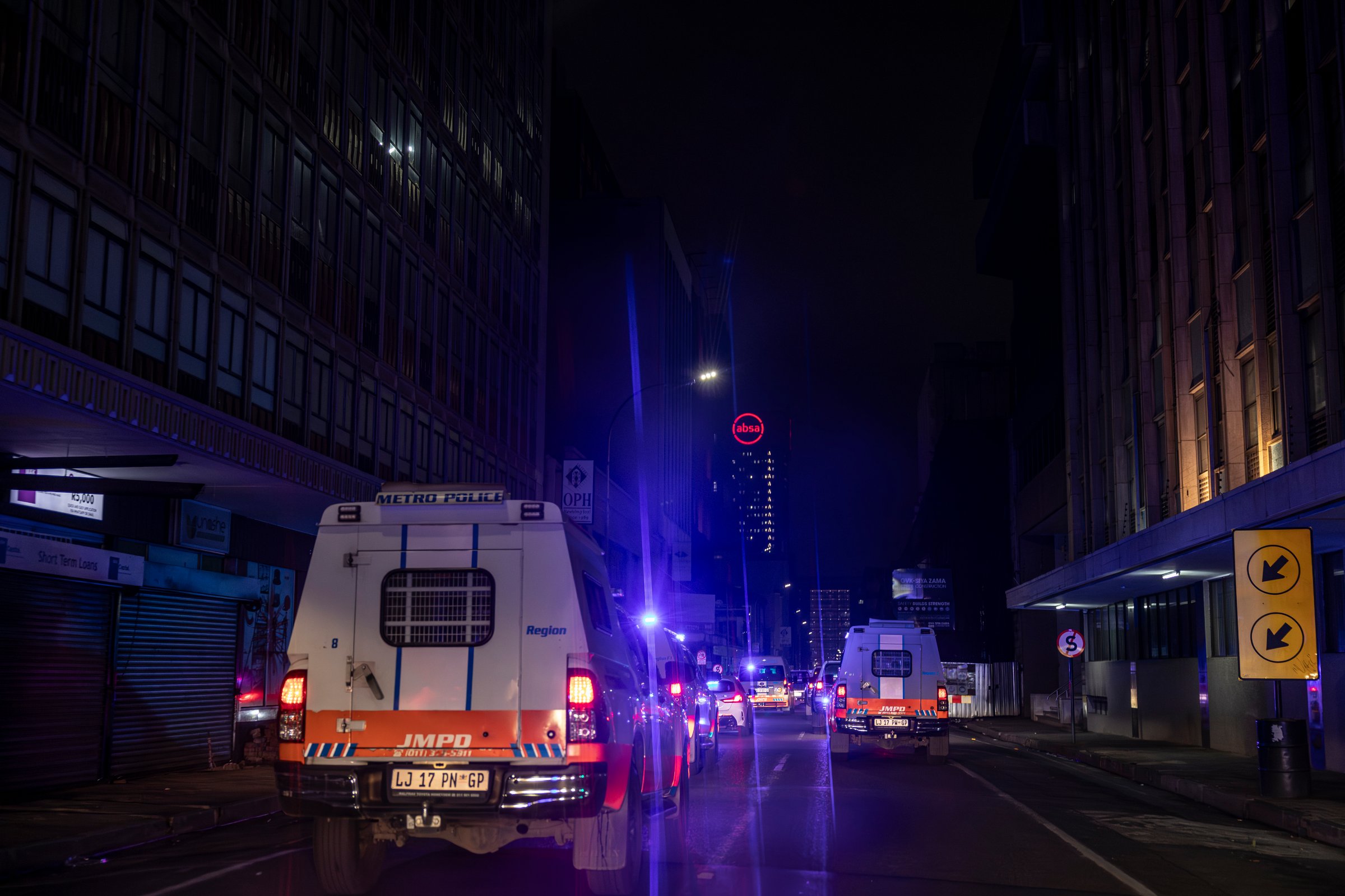 Un convoi de voitures de police se dirige vers un immeuble occupé illégalement dans le quartier central des affaires de Johannesburg (18 décembre 2025).