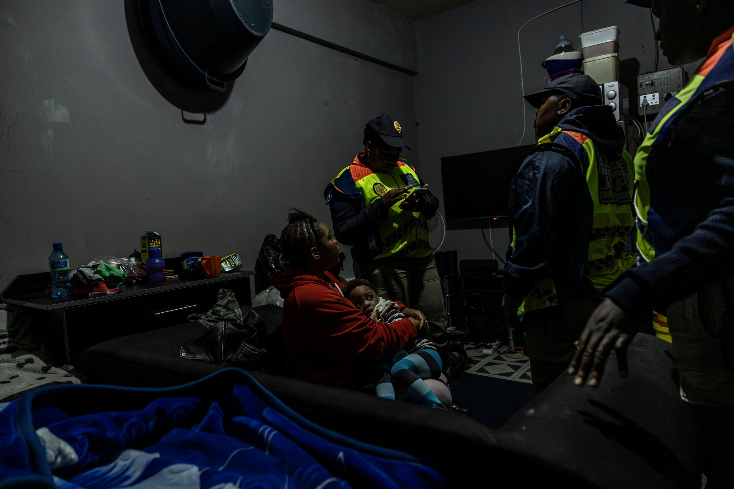 Des agents du Département de police métropolitaine de Johannesburg (JMPD) vérifient les papiers d'identité d'une mère dans un appartement d'un immeuble occupé illégalement (18 décembre 2025).