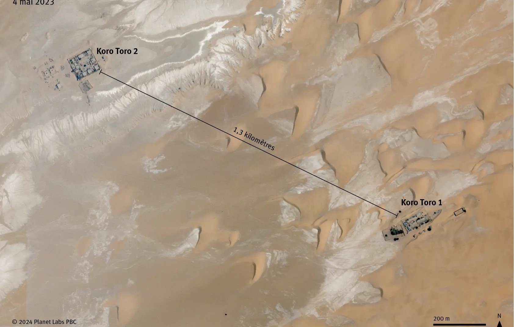 Cette image est une carte satellite des deux sites de la prison de Koro Toro, situés dans la région de Borkou au Tchad. On voit une étendue désertique avec des dunes de sable clair et des zones rocheuses. Les deux complexes de la prison, désignés comme Koro Toro 1 et Koro Toro 2, sont indiqués par des marqueurs. Koro Toro 2 est situé à l'ouest, tandis que Koro Toro 1 se trouve à l'est, séparés par une distance d'environ 1,3 kilomètre. En bas de l'image, il y a une échelle qui montre que la distance totale est de 200 mètres, et une orientation indiquant le nord. L'image a été prise le 4 mai 2023.