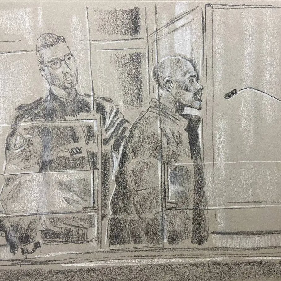 L'image représente une scène d'audience judiciaire. Au premier plan, on voit un homme debout, probablement un accusé, qui se tient derrière un panneau de séparation, exprimant une attitude sérieuse. Il est entouré par des éléments du tribunal, comme un microphone devant lui, indiquant qu'il pourrait s'exprimer. À sa gauche se trouve un policier en uniforme, affichant une posture attentive et vigilant. L'atmosphère de l'image est solennelle, reflétant le sérieux de la situation judiciaire. Les couleurs utilisées sont principalement des nuances de gris, et le style est esquissé, avec un rendu qui transmet les émotions et la tension de l'instant.