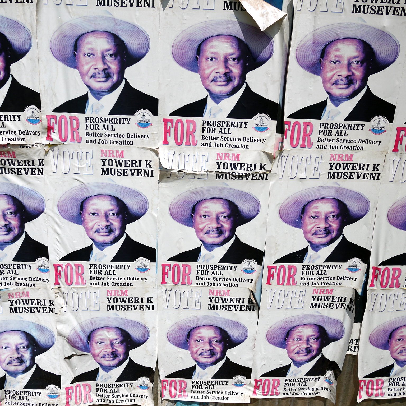 L'image montre un collage de plusieurs affiches sur un mur. Chaque affiche présente le même portrait d'un homme portant un chapeau de paille. Il a un grand sourire et affiche une expression confiante. Sous son image, on peut lire des textes en lettres majuscules qui soulignent des mots comme "PROSPERITY" (prospérité) et "FOR" (pour). Les affiches semblent faire partie d'une campagne politique, faisant appel au soutien des électeurs. Le fond est en papier décoloré et usé, indiquant que ces affiches ont été exposées pendant un certain temps.