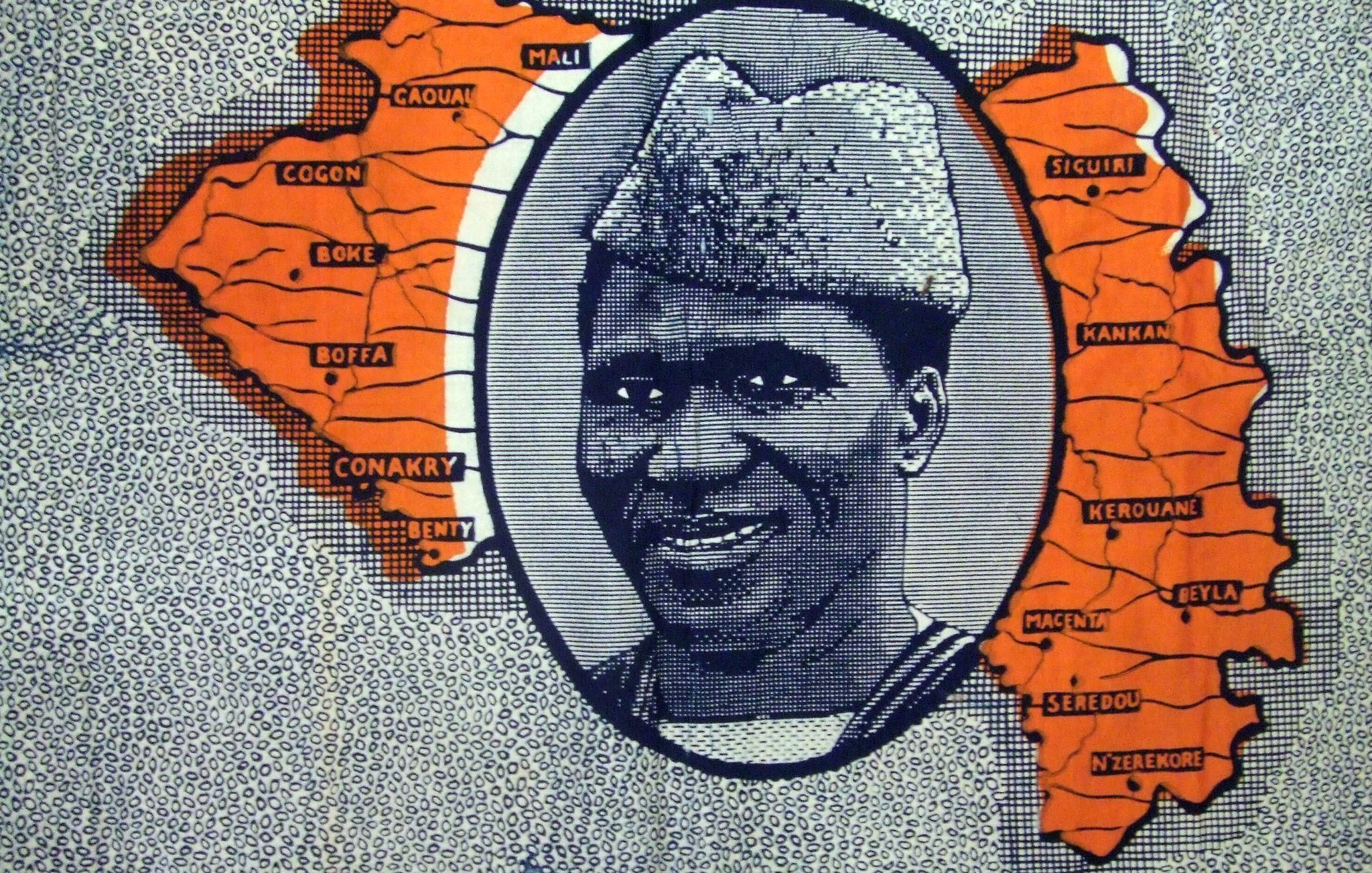 L'image que vous décrivez se compose principalement d'une carte stylisée de la Guinée, avec des contours et des noms de différentes régions. Au centre, il y a un portrait en noir et blanc d'un homme souriant, qui porte un chapeau caractéristique. Ce portrait est entouré d'un cadre ovale, et l'ensemble est mis en valeur par des zones colorées en orange sur la carte, qui semblent indiquer des localités spécifiques. Le fond est constitué de motifs répétitifs, créant une texture visuelle intéressante. Cette image évoque une célébration de la culture guinéenne, mettant en avant à la fois la géographie et une personnalité marquante.