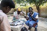 À droite, Adamou Garba, le président de la compagnie théâtrale Yal Hile, se maquille avant une représentation dans les rues de Bol.