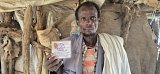 Tesheger Tagegne holds up the identity card of his wife, who died of a malnutrition-related illness.
