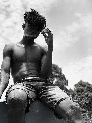Un adolescent travaillant sur une drague libérienne prend la pose. Fleuve Bandama, Côte d'Ivoire (2024).